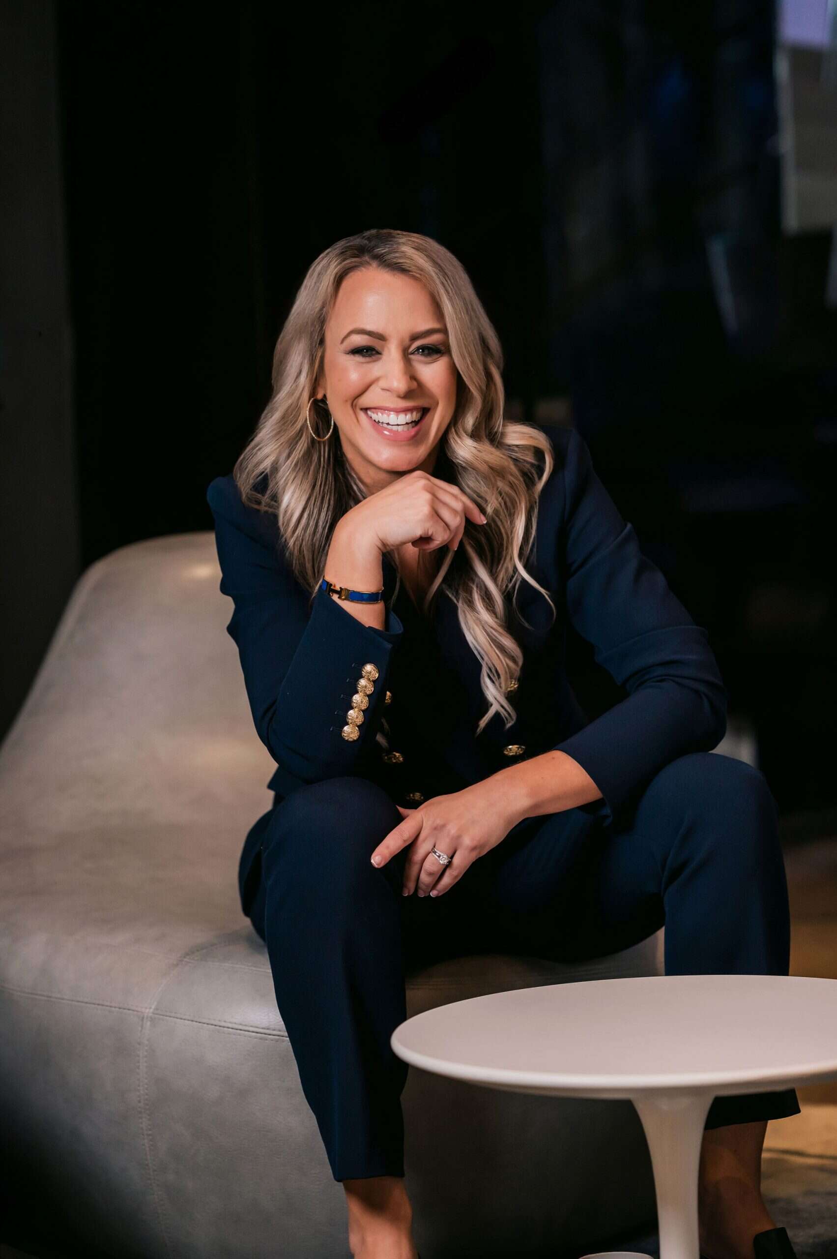 Marni Blythe laughing, seated in a navy suit